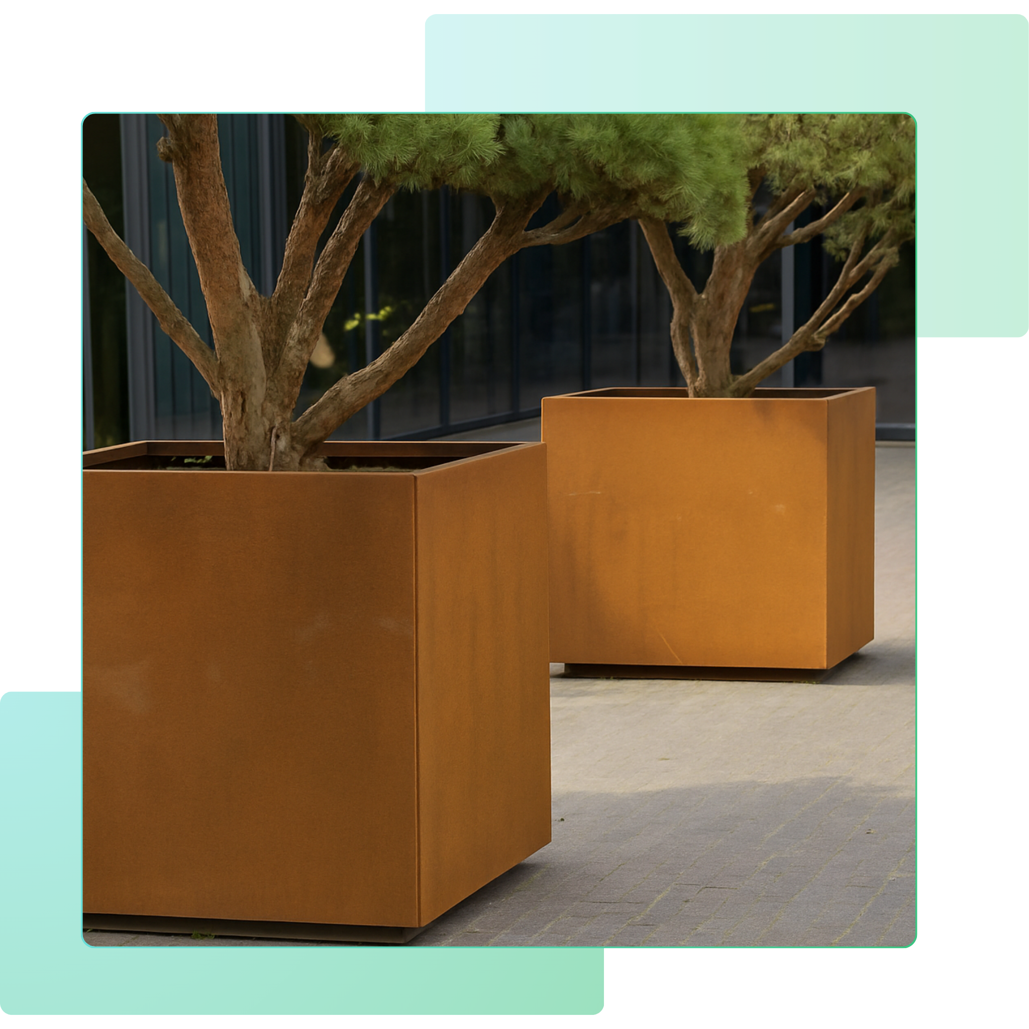 Zwei große Pflanzkübel aus Cortenstahl mit Bäumen auf heller Steinfläche, natürliche Rost-Patina als modernes Gartenelement.
